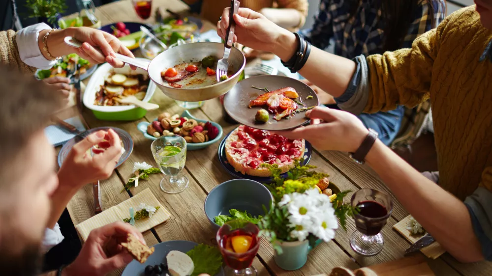 People sitting at dining table and eating / Foto: Shironosov
