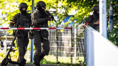Armed police officers patrol near the Schachen horse racing track in Aarau following a shooting during a rave event near Aarau, Switzerland, Sunday, Aug. 30, 2026. (Michael Buholzer/Keystone via AP)