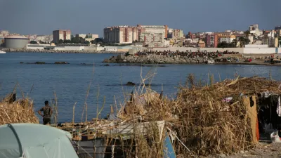 Makeshift shelters used by migrants line the coast as a crowd gathers on a breakwater in Ceuta, Spain, August 15, 2026. REUTERS/Maria Alejandra Cardona
