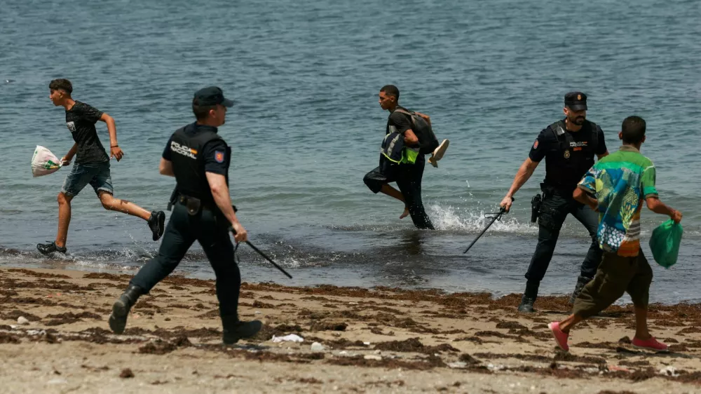 FILE PHOTO: Migrants try to make their way past Spanish police officers, following recent mass crossings of migrants on foot and by sea from Morocco into Spanish territory, in Ceuta, Spain, August 1, 2026. REUTERS/Violeta Santos Moura/File Photo