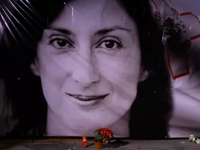 FILE - Flowers and a candle lie in front of a portrait of slain investigative journalist Daphne Caruana Galizia during a vigil outside the law courts in Valletta, Malta, Oct. 16, 2018. (AP Photo/Jonathan Borg, File)