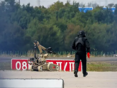 FILE PHOTO: A police officer in protective clothing walks next to an explosive-disarming robot (EOD) at Leipzig/Halle Airport in Schkeuditz, Germany, August 5, 2026, after the police said explosives experts examined a drone found near a runway, and after a DHL cargo aircraft hit an unknown object as it was climbing away from the airport overnight, prompting an unscheduled landing in Hanover, according to a source familiar with the incident. REUTERS/Axel Schmidt/File Photo