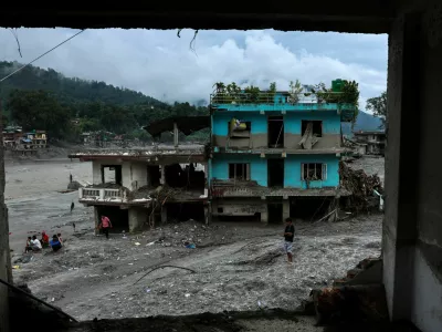 People next to damaged buildings near the Trishuli River, following the deadly flash floods and a mudslide, in Devighat, Nuwakot district, Nepal, September 4, 2026. REUTERS/Athit Perawongmetha