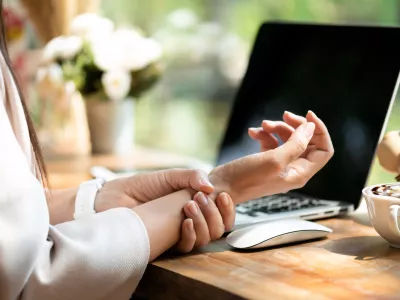 Closeup woman holding her wrist pain from using computer. Office syndrome hand pain by occupational disease.
