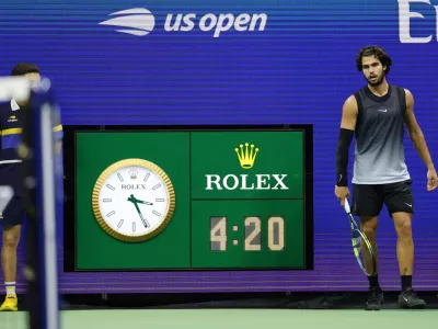 The clock reads 3:21 a.m. as Carlos Alcaraz, of Spain, plays in the fifth set against Ben Shelton, of the United States, during the quarterfinal round of the U.S. Open tennis championships, early Wednesday, Sept. 9, 2026, in New York. (AP Photo/Adam Hunger)