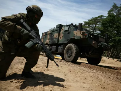 A Polish soldier kneels next to a military vehicle during the Bursztynowy Obronca-26 (Amber Defender-26) military exercise at the training ground in Klusy, Poland, June 24, 2026. REUTERS/Kacper Pempel