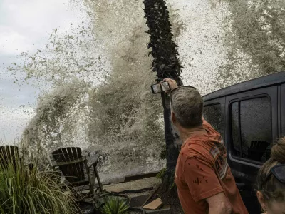 A Long Beach resident observes a crashing wave overtaking the sea wall. Hurricane Marie makes landfall in Long Beach, California.
