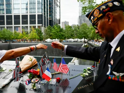 People join their hands as they pray for Father Mychal Judge, next to the reflecting pools at the 9/11 Memorial, during a ceremony marking the 25th anniversary of the September 11, 2001 attacks on the World Trade Center, in New York City, U.S., September 11, 2026. REUTERS/Jeenah Moon/Pool