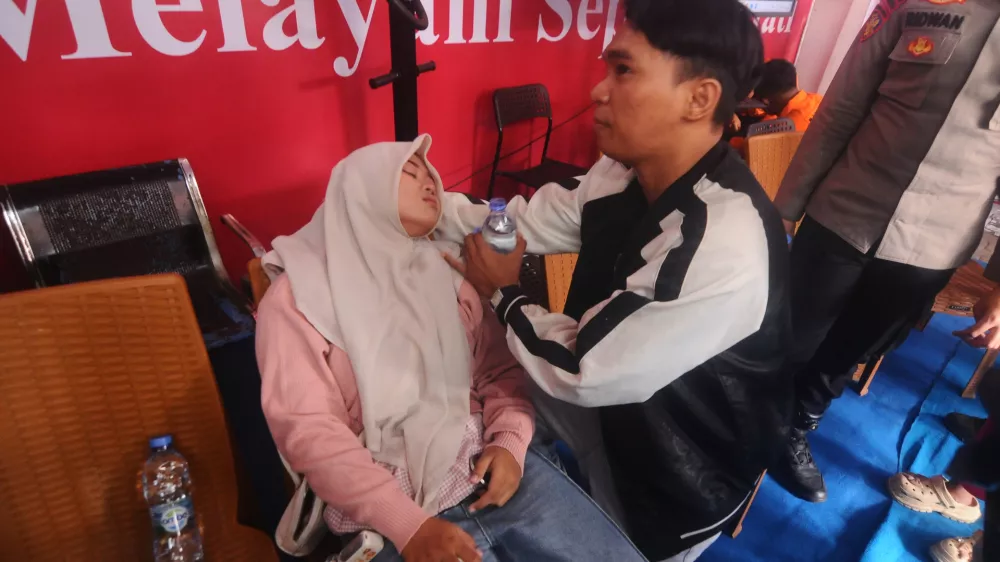 A woman loses consciousness upon learning that the name of a relative is on the passenger list of a ferry overturned in bad weather in the Java Sea, at the rescuers command center in Banjarmasin, South Kalimantan, Indonesia, Sunday, Sept. 13, 2026. (AP Photo/Iman Satria)