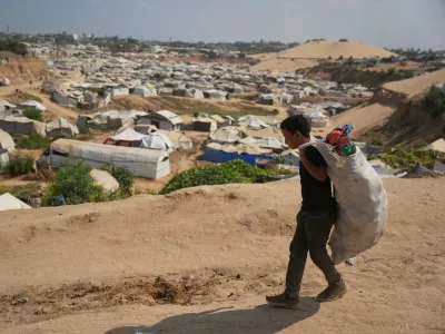 A Palestinian boy leaves a garbage dump after collecting combustible materials to use as fuel for cooking due to a shortage of cooking gas, in Deir al-Balah, central Gaza Strip, Saturday, Aug. 22, 2026. (AP Photo/Abdel Kareem Hana)