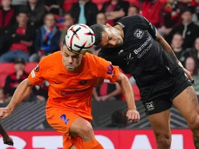 Celje's Pijus Sirvys, left, jumps for the ball with Leverkusen's Facundo Medina during the Europa League opening phase soccer match between Bayer Leverkusen and NK Celje in Leverkusen, Germany, Wednesday, Sept. 16, 2026. (AP Photo/Martin Meissner)