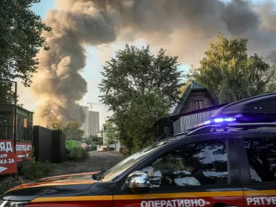 An emergency service vehicle drives by the site of a Russian drone strike as smoke rises in the background, amid Russia's attack on Ukraine, in Kyiv, Ukraine, September 16, 2026. REUTERS/Alina Smutko