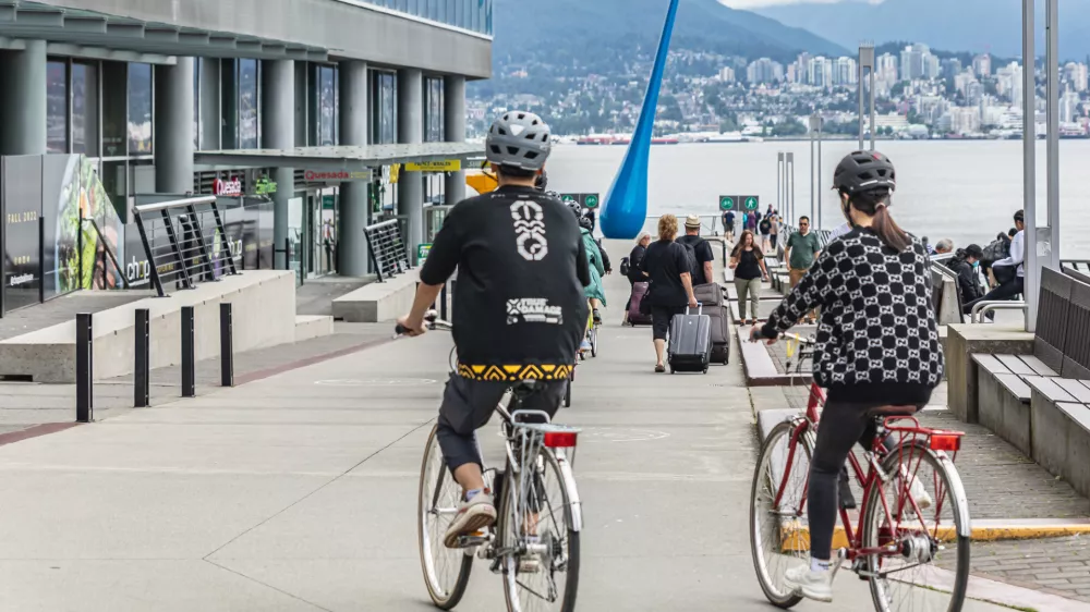 Young active couple in helmets riding on bicycles together on a street of the Vancouver city Canada. Sports, health, activity concept. Travel photo, editorial. July 10,2022
