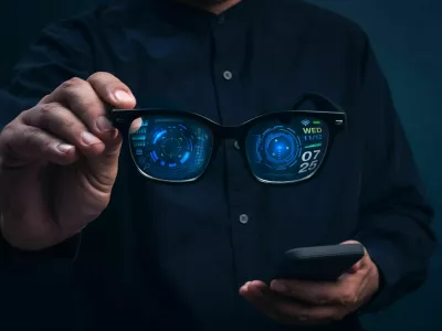 Smart glasses with augmented reality interface showing digital data and futuristic UI holding in businessman hands. Concept of wearable technology, AR innovation, and next-generation smart devices. / Foto: Techa Tungateja