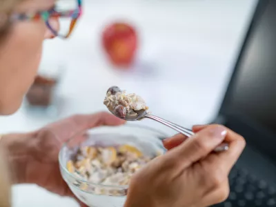 The perfect balance of work and wellness as a woman embraces healthy eating at her workplace. With a bowl of nutritious muesli and yogurt in her hand, optimizing her productivity / Foto: Microgen Getty Images