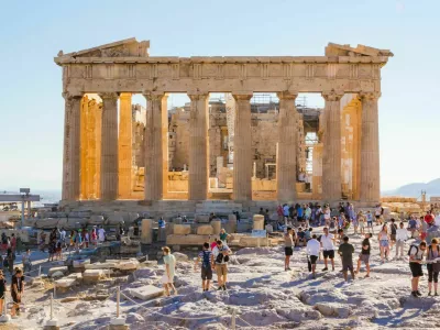 Crowds of tourists visit everyday the Parthenon in the Acropolis in Athens, Greece. At sunset heat decreases and shadows are long.