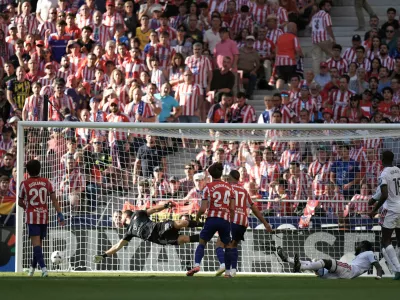 Real Madrid's Antonio Rudiger, on the ground, scores his side's first goal past Atletico Madrid's goalkeeper Jan Oblak during a Spanish La Liga soccer match between Atletico Madrid and Real Madrid in Madrid, Sunday, Sept. 20, 2026. (AP Photo/Bernat Armangue)