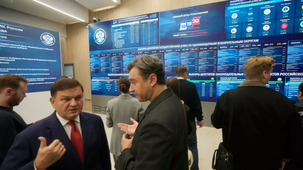 People stand next to video screens sowing preliminary voting results for Russian parliamentary elections at Russia's Central Election Committee headquarters, in Moscow, Russia, Monday, Sept. 21, 2026. (AP Photo/Pavel Bednyakov)