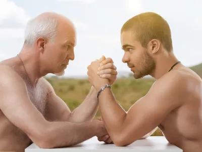 Intense arm wrestling match between elder and younger bare-chested men / Foto: Giulio Fornasar