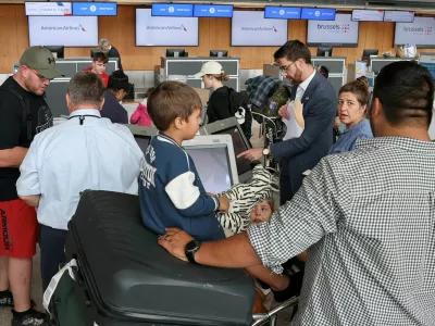 FILE PHOTO: A U.S. State Department official helps people from the first group of white South Africans granted refugee status for being deemed victims of racial discrimination under U.S. President Trump's Refugee plan, check in for a connecting flight, at Dulles International Airport, in Dulles, Virginia, U.S., May 12, 2025. REUTERS/Jonathan Ernst/File Photo