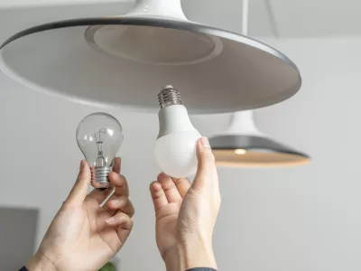 Energy saving idea: Asian people replace fluorescent light bulbs (CFL) with new LED bulbs. Female hands screw in an energy-saving LED light bulb. / Foto: Jittawit.21 Getty Images