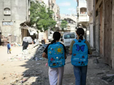 GAZA, PALESTINE - SEPTEMBER 26: Palestinian students walk through the damaged streets of the Sheikh Radwan neighborhood in northern Gaza carrying UNICEF school bags decorated with colorful designs by artist Sara Zakkut, on September 26, 2026 in Gaza, Palestine. The 21-year-old artist decorates school bags distributed by UNICEF to lift the spirits of children living amid a severe humanitarian crisis and shortages of basic necessities under the Israeli blockade. Zakkut continues her work inside a heavily damaged building, seeking to support students struggling to continue their education despite ongoing Israeli attacks. Abdalhkem Abu Riash / AnadoluNo Use USA No use UK No use Canada No use France No use Japan No use Italy No use Australia No use Spain No use Belgium No use Korea No use South Africa No use Hong Kong No use New Zealand No use Turkey / Foto: Abdalhkem Abu Riash