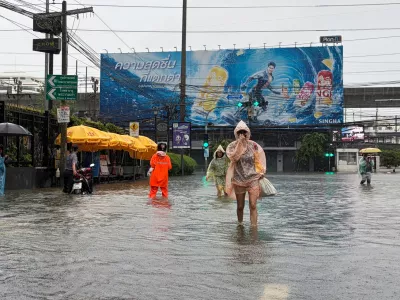 In this photo taken with a smartphone, people wade through floodwaters after heavy rain in Bangkok, Thailand Saturday, Sept. 26, 2026. (AP Photo/Adam Schreck)
