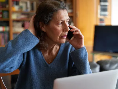 Stressed senior businesswoman on the phone while working on laptop