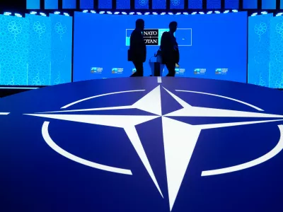 Two men walk past the NATO logo during the NATO Defense Industry Forum at the NATO summit in Ankara, Turkey, Tuesday, July 7, 2026. (AP Photo/Hussein Malla)