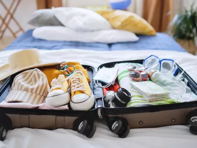 An open suitcase packed for holiday on bed at home, coronavirus concept.