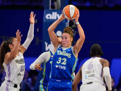 Dallas Wings' Jessica Shepard (32) looks to make a pass after collecting a rebound between Golden State Valkyries' Veronica Burton (22) and Kaila Charles (6) during the second half of a WNBA basketball first-round playoff game Wednesday Sept. 30, 2026, in Arlington, Texas. (AP Photo/Tony Gutierrez)