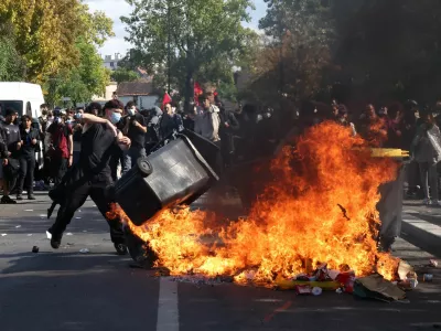 A masked protester throws a garbage bin into a fire set up by high school and university students in a street amid clashes with French riot police during a student protest to demand the hiring of substitute teachers, increased resources and better learning conditions, and to support the ongoing high-school student movement in the Seine-Saint-Denis department, in Saint-Denis near Paris, France, October 1, 2026. REUTERS/Abdul Saboor