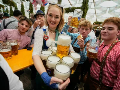 A waitress carries beer mugs after the opening of the 191st Oktoberfest beer festival in Munich, Germany, Saturday, Sept.19, 2026. (AP Photo/Matthias Schrader)