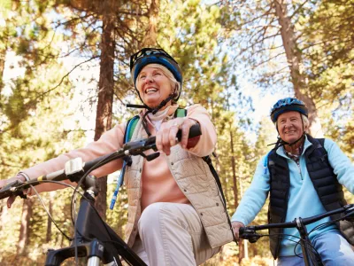 Senior couple mountain biking on a forest trail, low angle