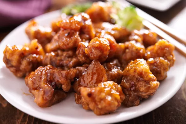 chinese orange chicken with chopsticks on round plate / Foto: Rez-art