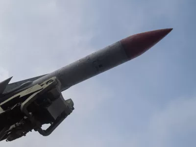 red nosed missile angled toward sky with launcher mechanism visible, closeup of seeker tip and aerodynamic