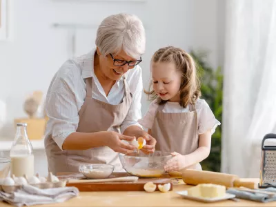 Happy loving family are preparing bakery together. Granny and child are cooking cookies and having fun in the kitchen.