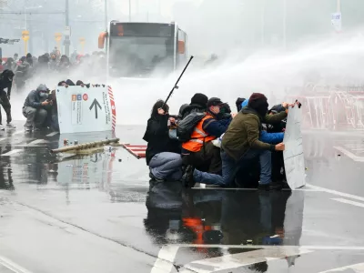 Demonstrators try to get cover from police water cannons as student protesters join a nationwide strike against the Belgian government's austerity measures and budget cuts, in Brussels, Belgium, October 9, 2026. REUTERS/Yves Herman