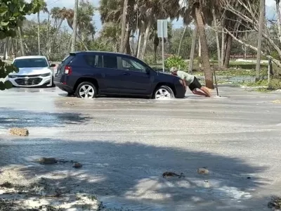 A man tries to push a car as waves wash over the road ahead of the arrival of Hurricane Isaias, in Englewood, Florida, US, October 9, 2026. Englewood Area Fire Control District via Facebook/Handout via REUTERS  THIS IMAGE HAS BEEN SUPPLIED BY A THIRD PARTY. NO RESALES. NO ARCHIVES. MANDATORY CREDIT. Verification lines: Buildings, electricity poles, road signs, road layout and trees matched file and satellite images in the area. Date verified by government reports of Manasota Key Road in Englewood, Florida was closed due to waves washing over road. The US National Hurricane Center said Hurricane Isaias made landfall in western Florida panhandle, warning of danger from storm surges and floods.