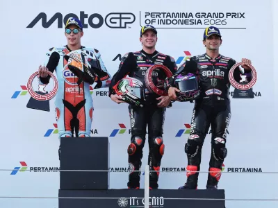 MotoGP - Indonesian Grand Prix - Mandalika International Street Circuit, Mandalika, Indonesia - October 11, 2026 Aprilia Racing's Marco Bezzecchi celebrates on the podium with a trophy after winning the MotoGP race with second place Trackhouse MotoGP Team's Raul Fernandez and third place Aprilia Racing's Jorge Martin REUTERS/Willy Kurniawan   TPX IMAGES OF THE DAY