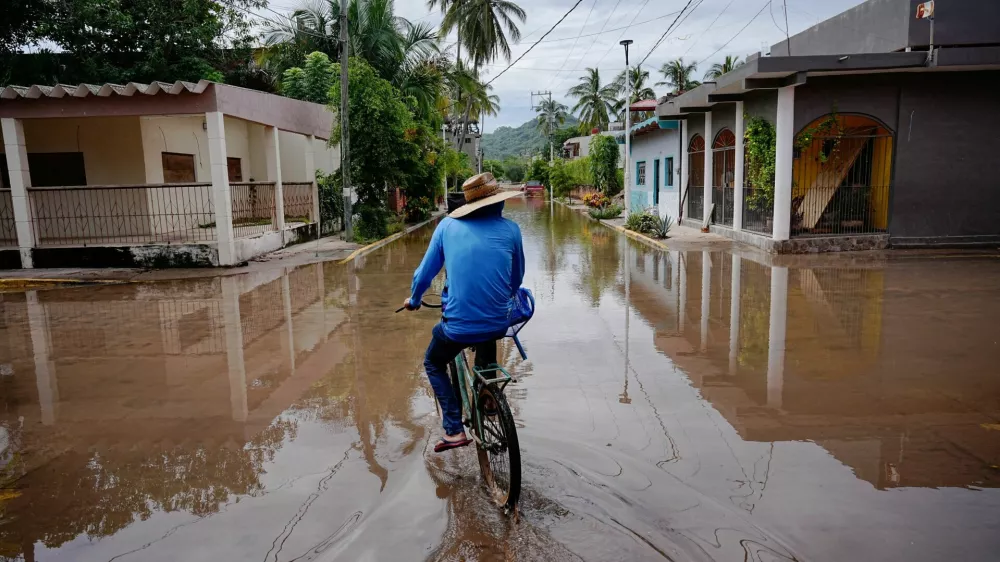 A person rides a bicycle through a flooded street as Hurricane Simon remains off Mexico's Pacific coast, in San Francisco, Bahia de Banderas, Nayarit state, Mexico, October 12, 2026. REUTERS/Christian Ruano   TPX IMAGES OF THE DAY