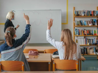 Two girl students during a classroom lecture, listening and communicating with a teacher. Education and learning concept.