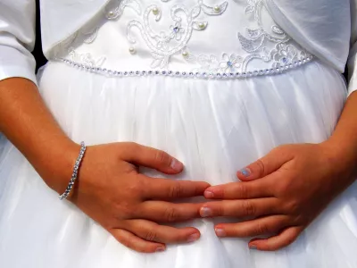 Cute little cild bridesmaid in white dress with hands on her belly