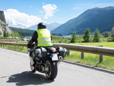 Motorbiker is riding his motorcycle on winding roads through the mountains in the summer sun