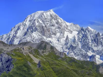 Panoramic view of snow-capped mountains and green valleys under a clear blue sky