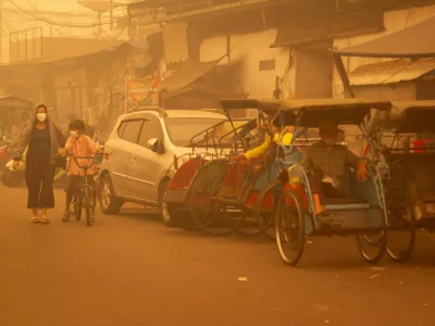 People wearing protective masks walk through the street as haze from wildfires shrouds the area in Palangka Raya, Central Kalimantan province, Indonesia, October 14, 2026. REUTERS/Arief Rahman Septian Prathama