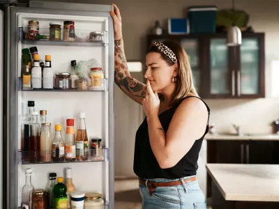 Shot of a young woman searching inside a refrigerator at home