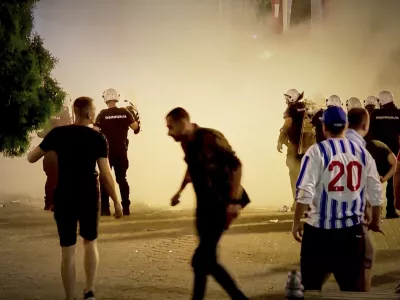 An image taken from video shows protesters and riot police engulfed by smoke as clashes erupted at protests in Vrbas, Serbia, Tuesday, Aug. 12, between opponents and supporters of the government in an escalation of tensions following more than nine months of persistent demonstrations against populist President Aleksandar Vucic. (N1 Serbia via AP)