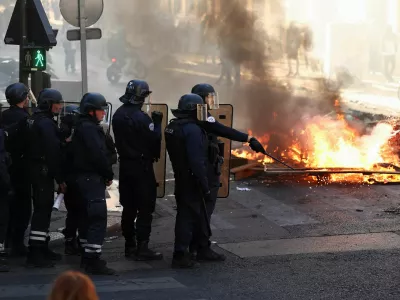 Francoski policisti stojijo zraven požara. 