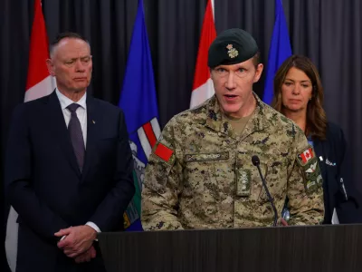 Major-General L.W. Rutland, center, speaks as Canada National Defence Minister David McGuinty, left, and Alberta Premier Danielle Smith, right, listen during a news conference in Edmonton, Alberta, Sunday, Oct. 18, 2026. (James Maclennan/The Canadian Press via AP)